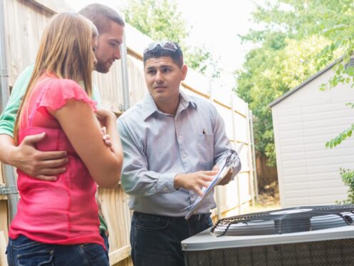 Air Conditioner repairman explaining cost of repairs to homeowners
